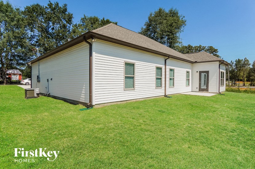 a small white house with green shutters on the side of a grass field