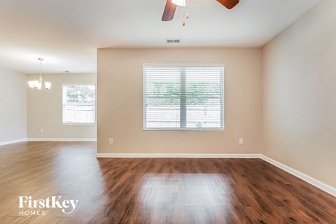 an empty living room with wood floors and a window