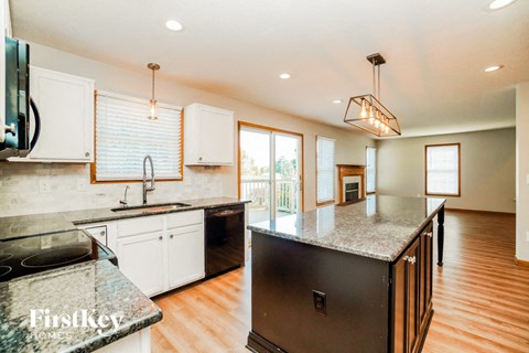 A kitchen with a black fridge and a granite counter top.