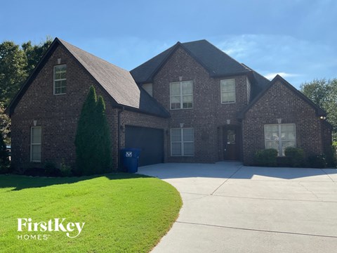 a large brick house with a driveway and a lawn