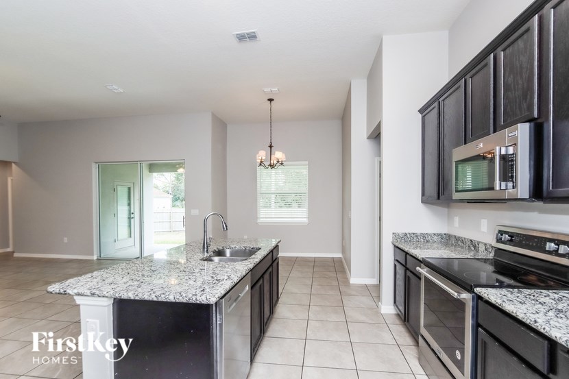 A kitchen with granite countertops and black cabinets.