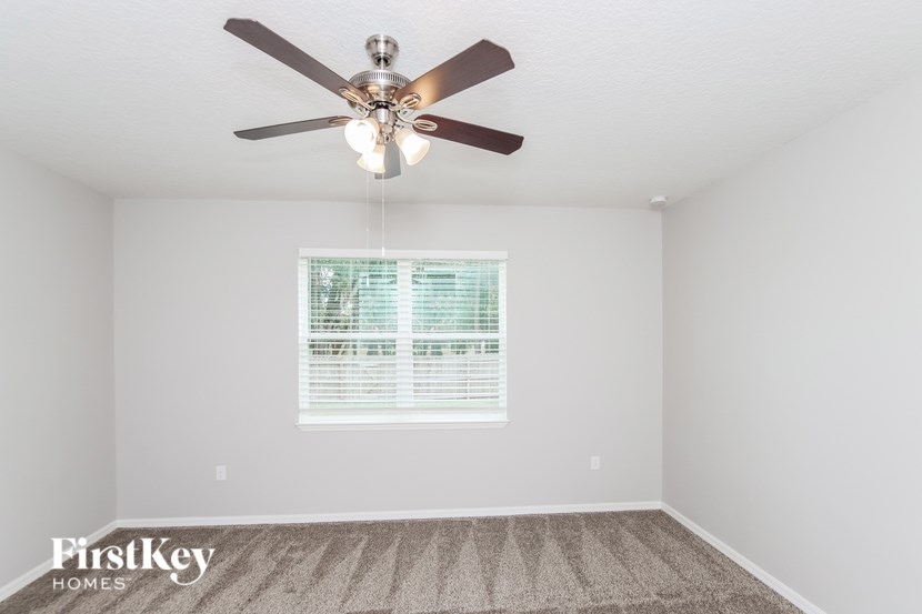 A room with a ceiling fan and a window with blinds.