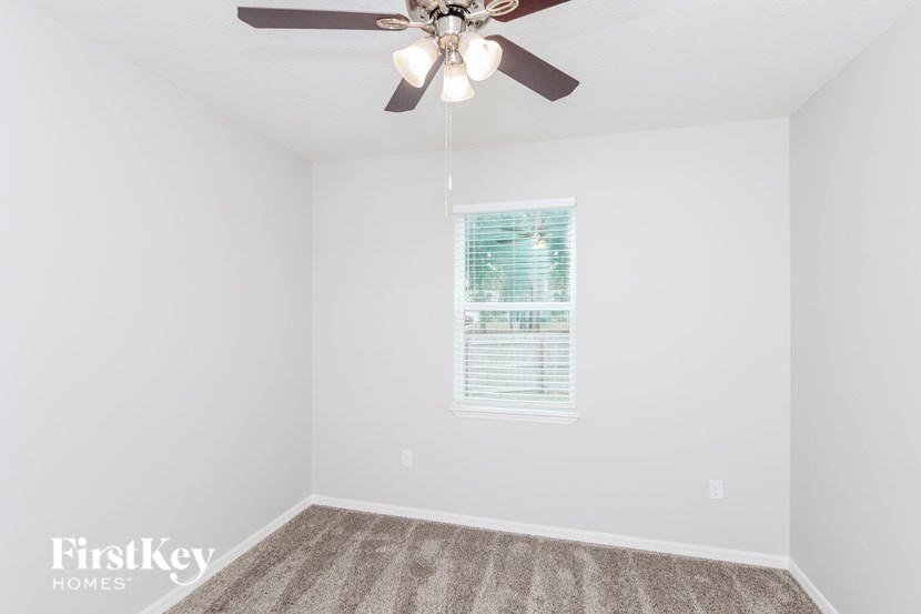 A room with a ceiling fan and a window with blinds.