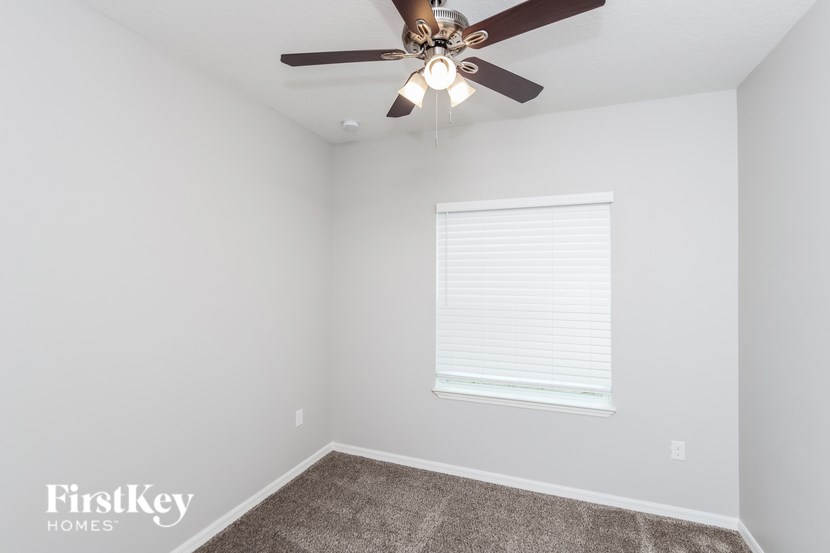 A room with a ceiling fan and a window with blinds.