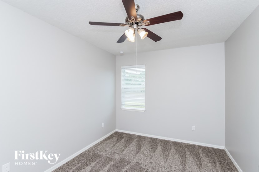 A room with a ceiling fan and a window with blinds.