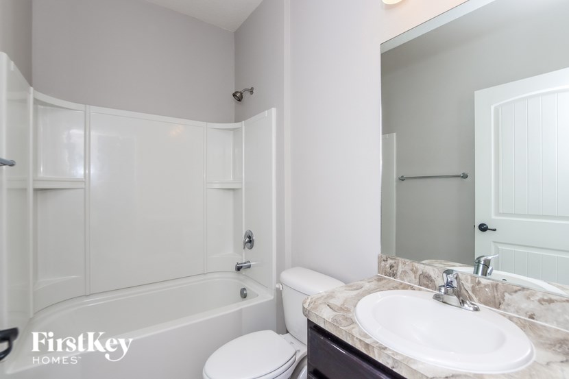 A white bathroom with a toilet, sink, and bathtub.