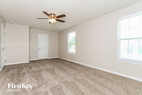 a living room with carpet and a ceiling fan
