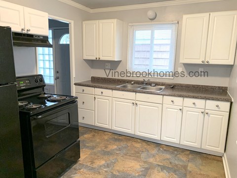 A kitchen with black appliances and white cabinets.