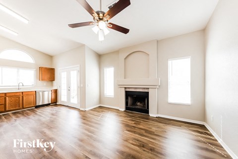 A spacious living room with a fireplace and a ceiling fan.