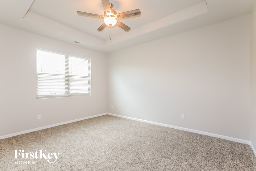 an empty room with a ceiling fan and a window