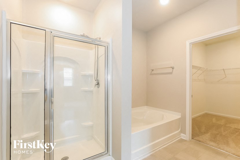 a bathroom with a shower and a tub and a closet