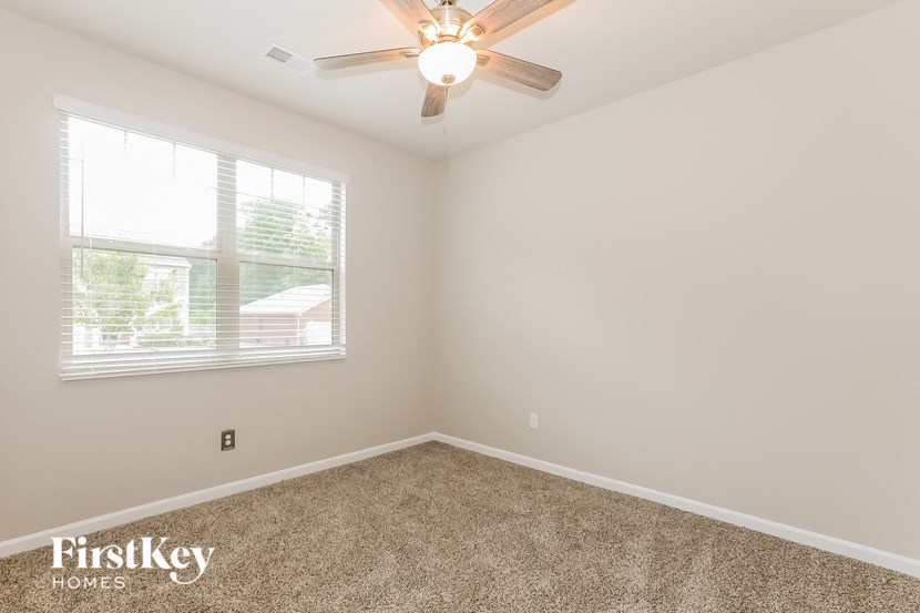 the living room of a home with carpet and a ceiling fan