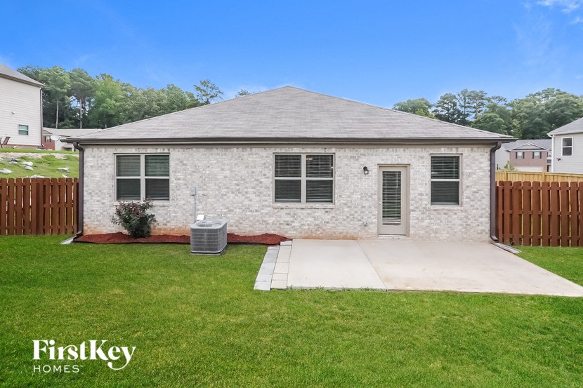 a small white brick home with a yard and a sidewalk