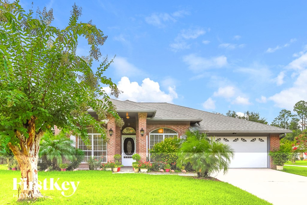 a house with a lawn and palm trees in front of it