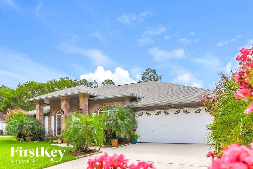 a house with a garage and palm trees in front of it