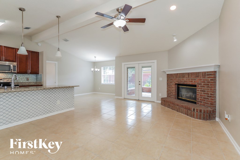 a large living room with a brick fireplace and a ceiling fan
