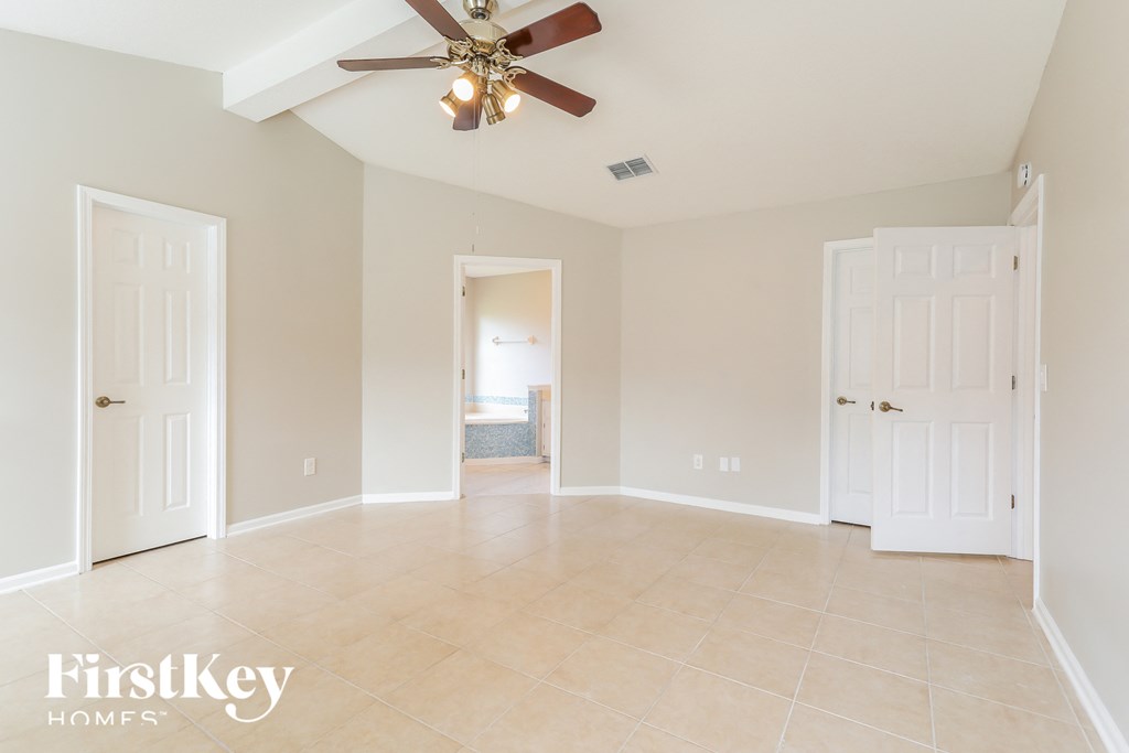 an empty living room with a ceiling fan and a door to a bathroom