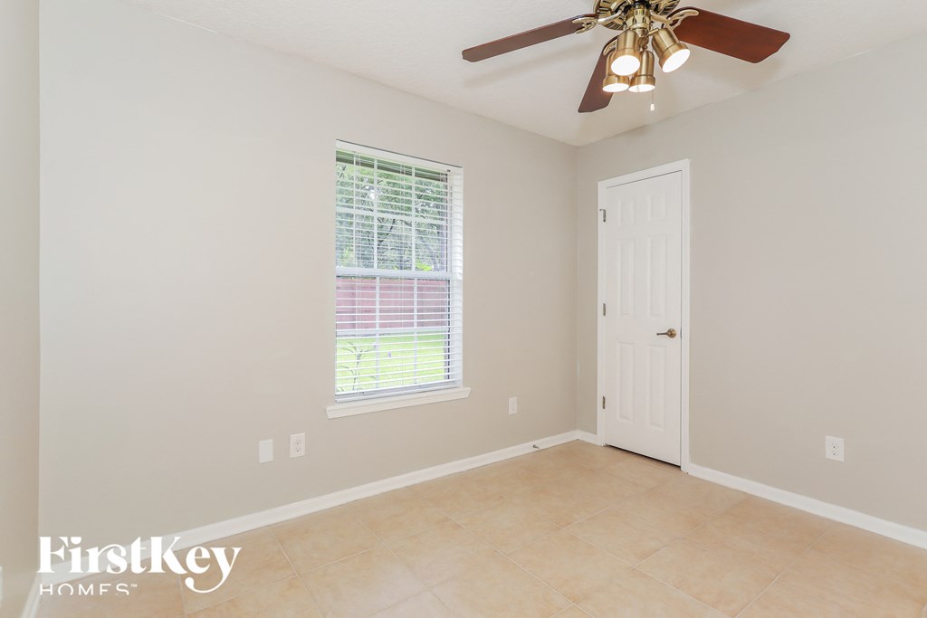 a clean and empty room with a ceiling fan and a window