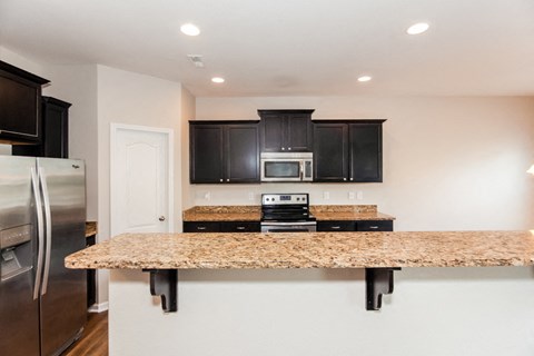 A kitchen with a granite counter top and stainless steel appliances.