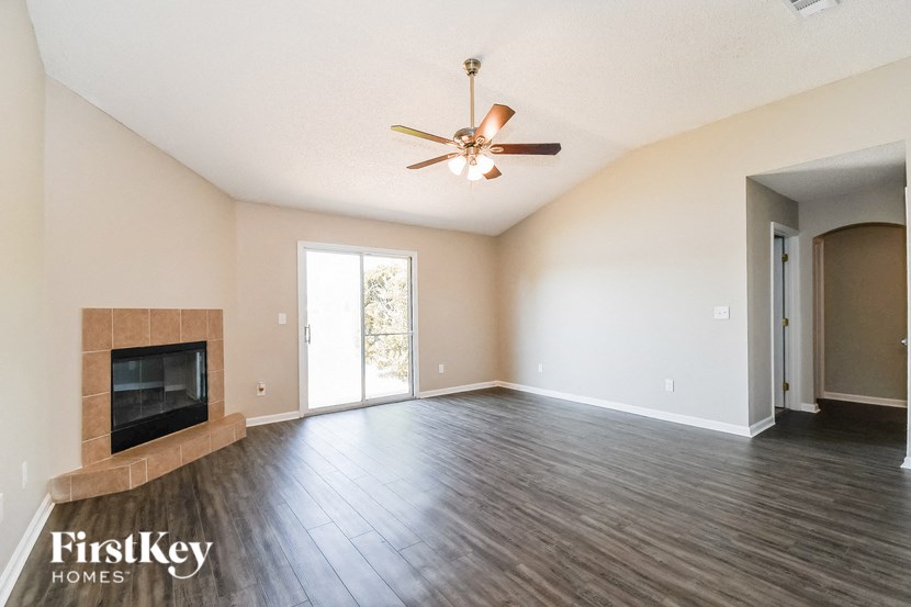 an empty living room with a fireplace and a ceiling fan