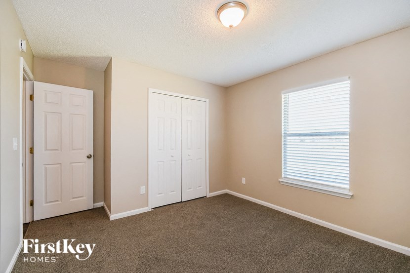 a bedroom with carpet and a door and a window