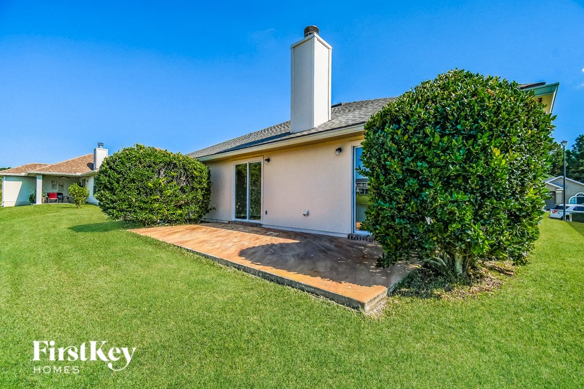 a small white house with a yard and a green tree