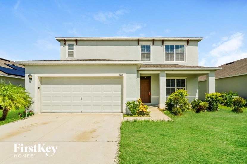 A white house with a garage door and a brown door.