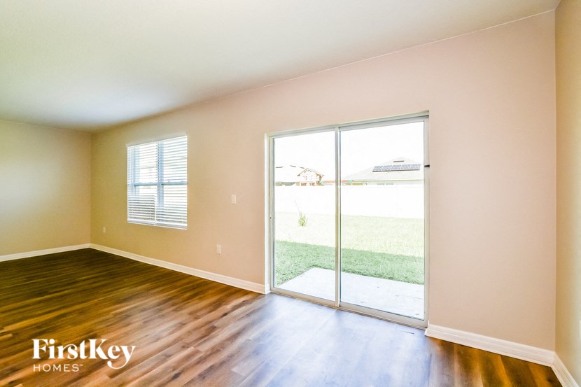 A room with wooden floors and a sliding glass door leading to a backyard.