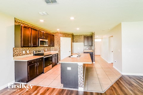 A kitchen with dark wood cabinets and a tiled backsplash.