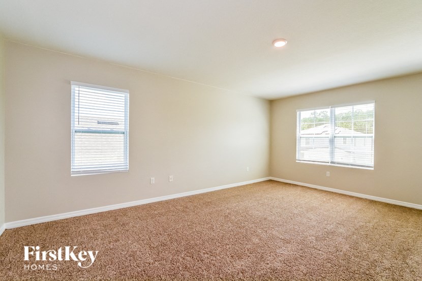 A room with a carpeted floor and two windows.