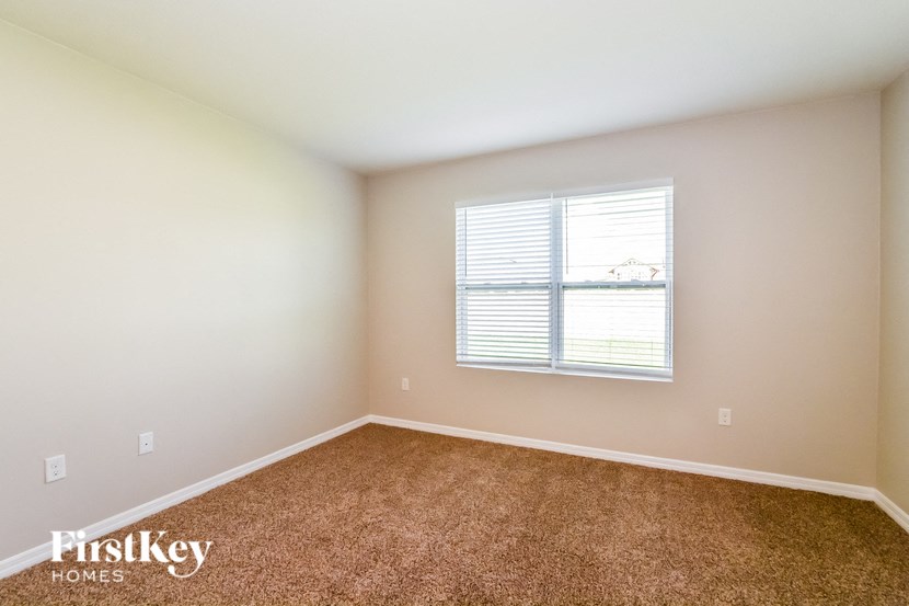 A room with a carpeted floor and a window with blinds.