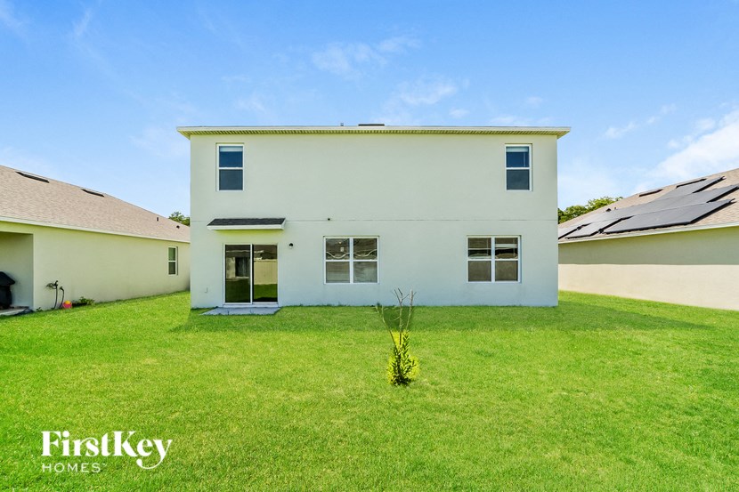 A white house with a green lawn in front of it.