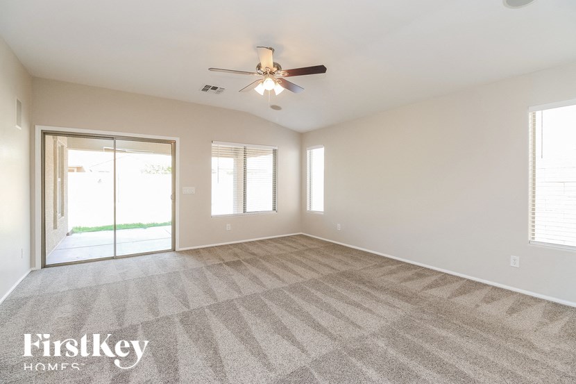 A spacious room with a carpeted floor and a ceiling fan.