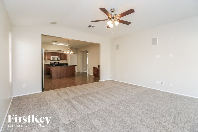 A spacious room with a carpeted floor and a ceiling fan.