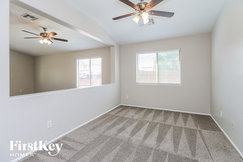 A spacious room with a ceiling fan and carpeted floor.