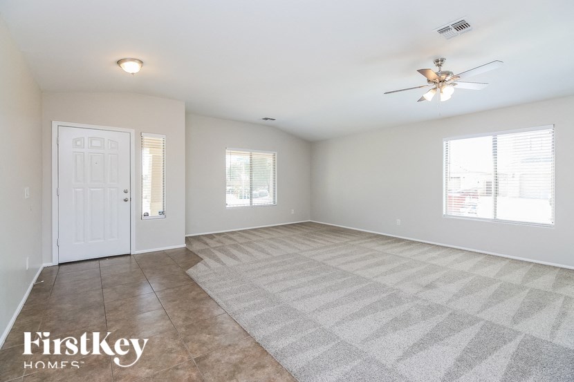 A spacious room with a rug on the floor and a ceiling fan.