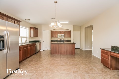 A kitchen with a refrigerator, wooden cabinets, and a marble countertop.