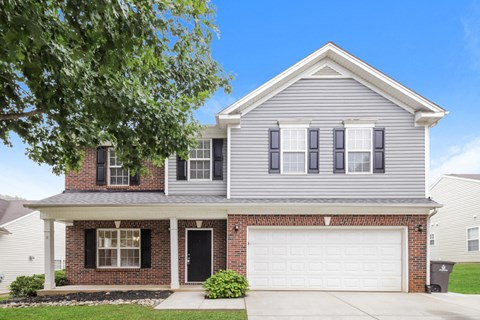 A two-story house with a garage and a brick base.