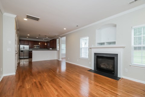 A large, empty living room with a fireplace and hardwood floors.