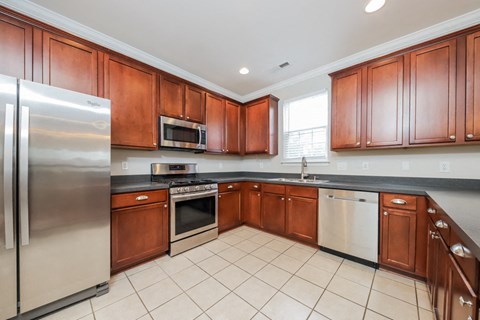 A kitchen with wooden cabinets and a stainless steel refrigerator.