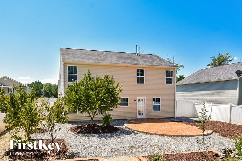 a beige house with a gravel yard and a driveway