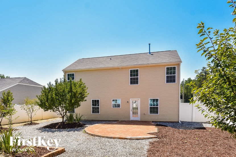 a white house with a gravel yard and a driveway