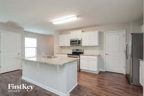 A kitchen with white cabinets and a granite countertop.