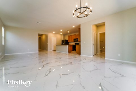 an empty living room and kitchen with marble flooring