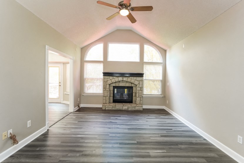 a empty living room with a fireplace and a ceiling fan