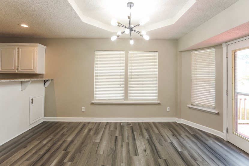 an empty living room with wood floors and a kitchen