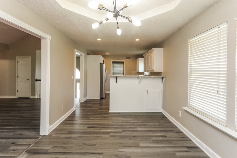 an empty living room and kitchen with a ceiling fan