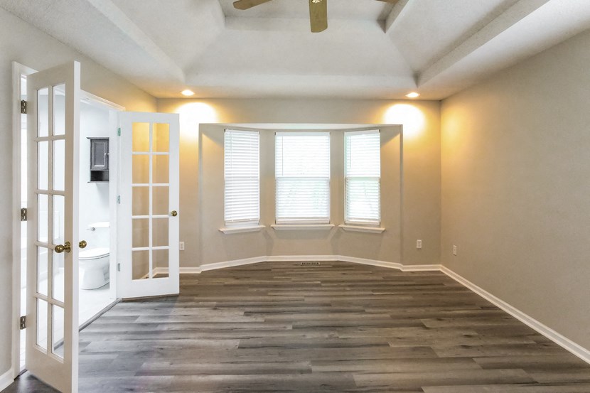 an empty living room with a white door and window