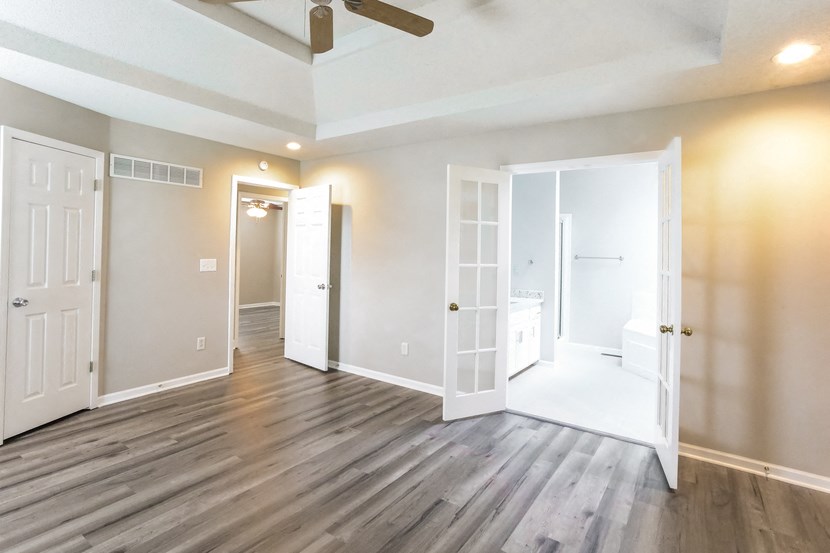 an empty living room with white doors and a ceiling fan