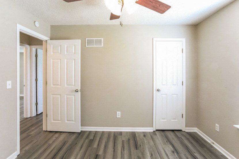 an empty living room with two doors and a ceiling fan